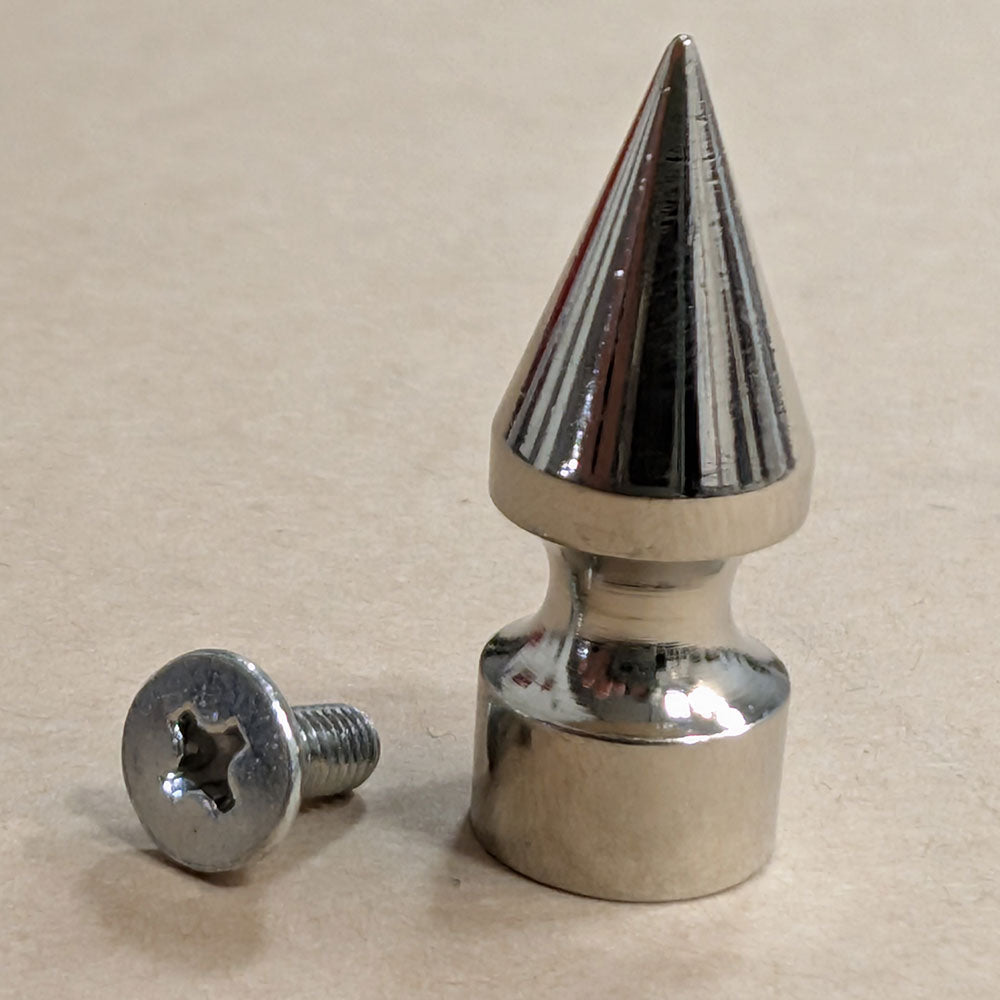 Metallic spike and screw on a beige background