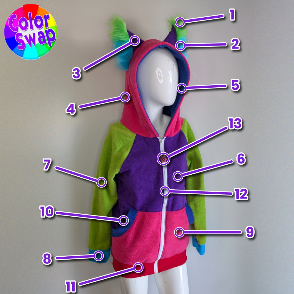 A colorful hooded one-piece outfit displayed on a white mannequin against a plain light gray wall. The garment has a bright pink hood with fluffy ears, lime green sleeves, a purple front panel, and pink lower section, with numbered callout lines pointing to different parts.
