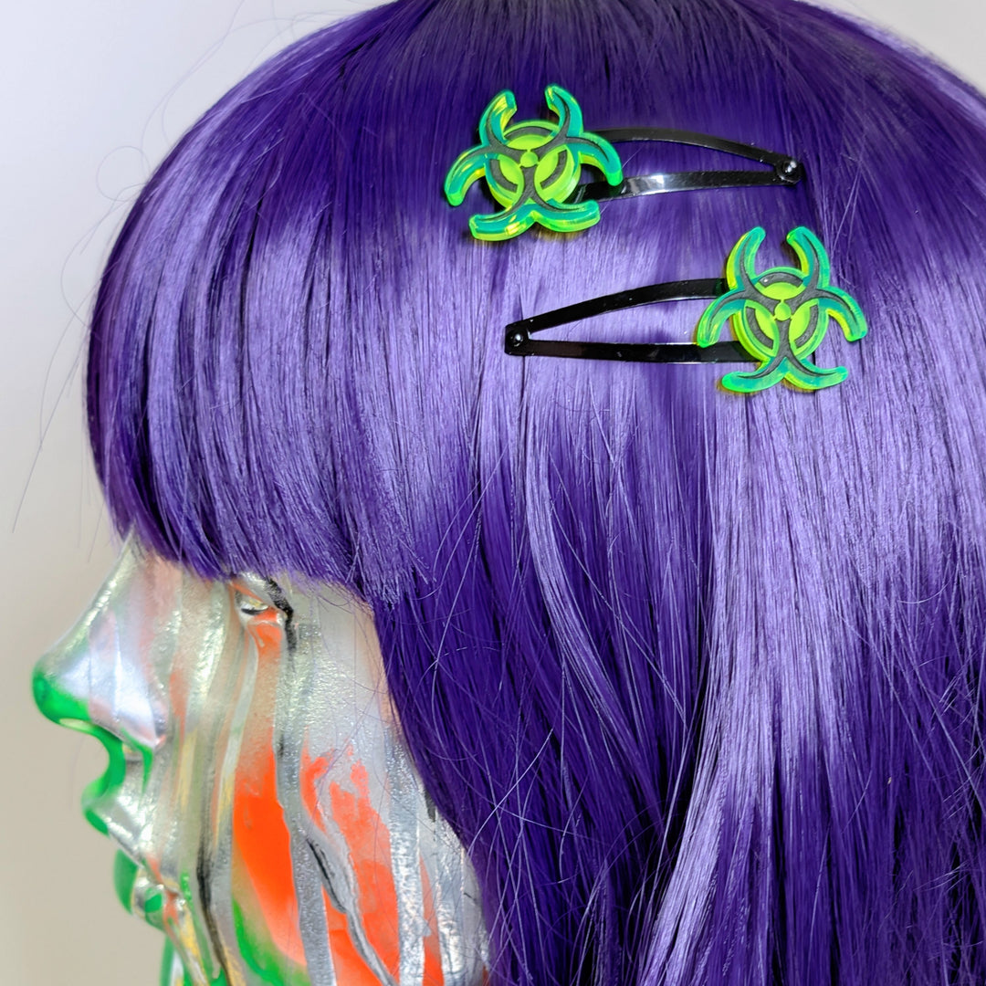 Purple wig with green biohazard symbol hair clips on a white background