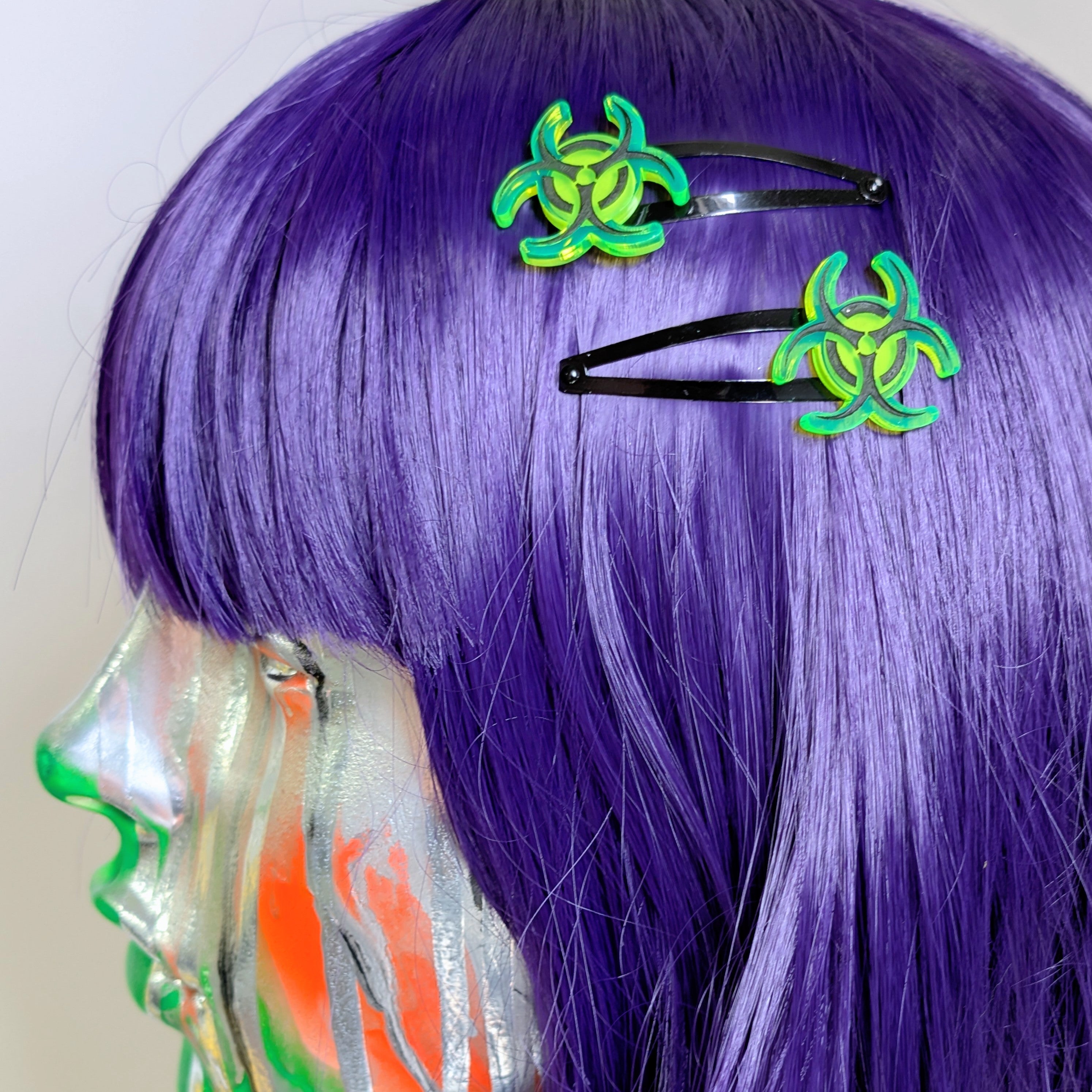 Purple wig with green biohazard symbol hair clips on a white background