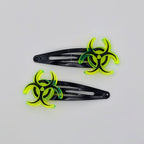 Two black hair clips with green biohazard symbol on a white background