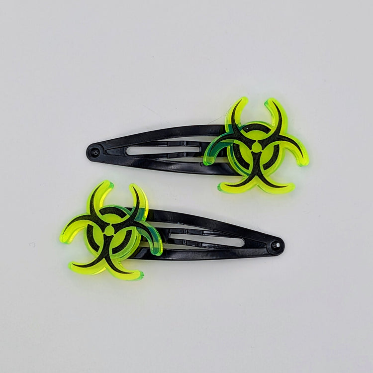 Two black hair clips with green biohazard symbol on a white background